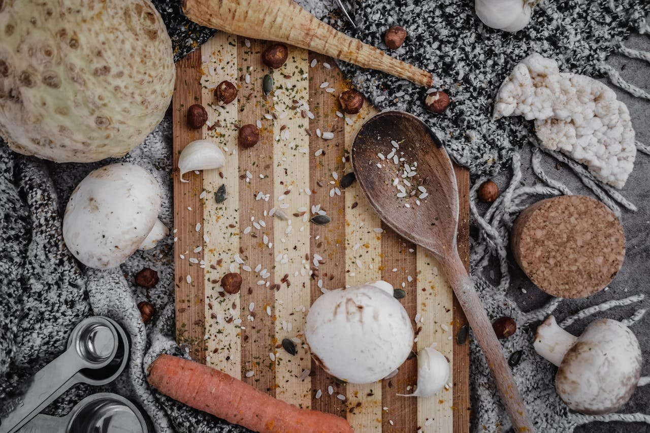 Top view of a rustic kitchen setup with various ingredients and a wooden spoon on a chopping board.